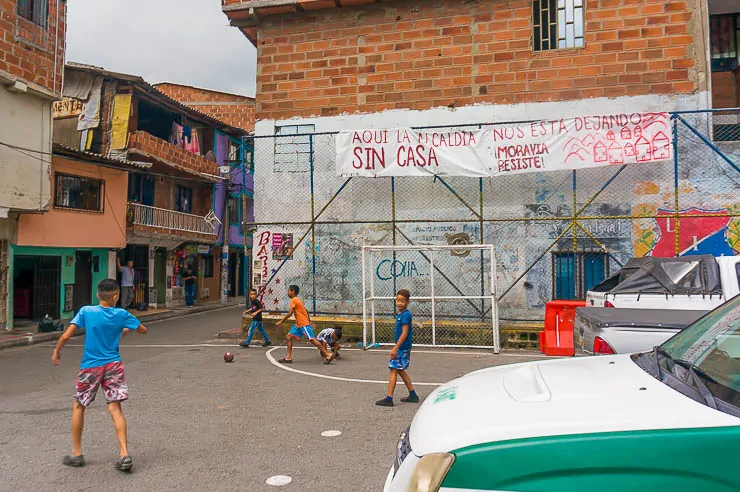 Children playing soccer on a tiny lot with a sign of the resistance for Moravia Medellin