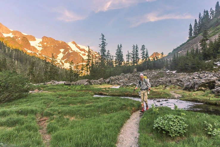 Hiking out of the Cascades as the sun begins to set on the snow covered mountains. Day hiking essentials