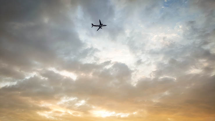 Plane flying against the clouds at sunset